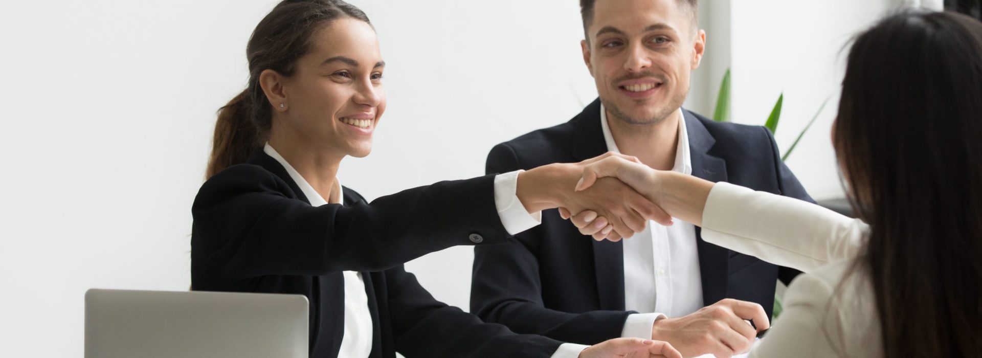 Smiling HR managers greeting female job applicant with handshake during recruiting or interview. Businesswoman making good first impression shaking hands of business partners. Partnership, cooperation